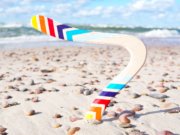 Dvisakis-bumerangas-Vejas-ismeigtas-smelyje Spalvotas bumerangas „Vėjas“ įsmeigtas į pajūrio smėlį.