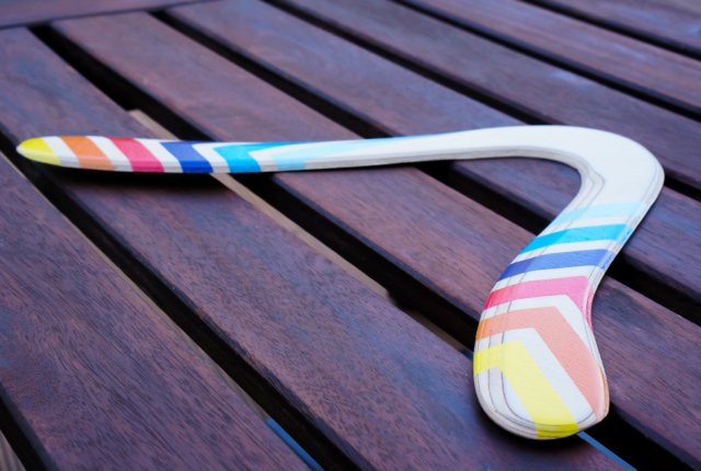 Kokybiskas-medinis-bumerangas-Vejas-ant-stalo Medinis bumerangas „Vėjas“ ant rudo lauko stalo – matoma medienos tekstūra.